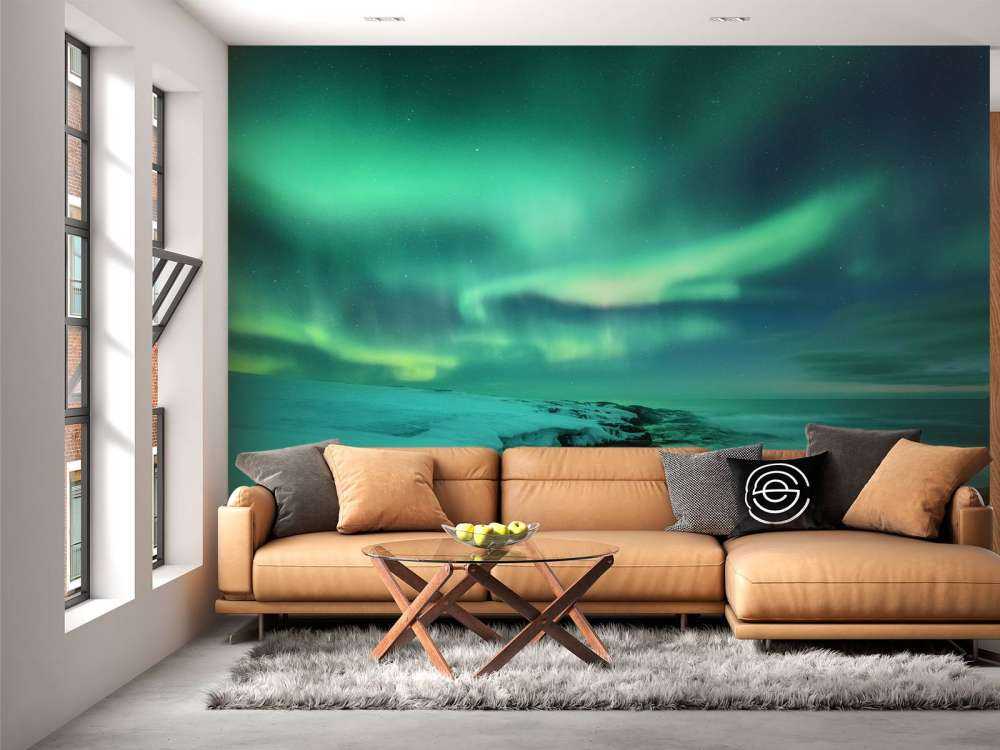 Aurora boreale verde sopra le rocce innevate