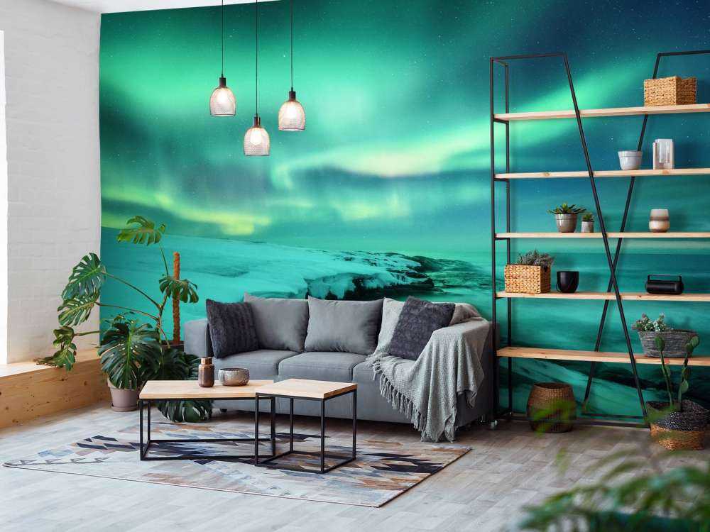 Aurora boreale verde sopra le rocce innevate