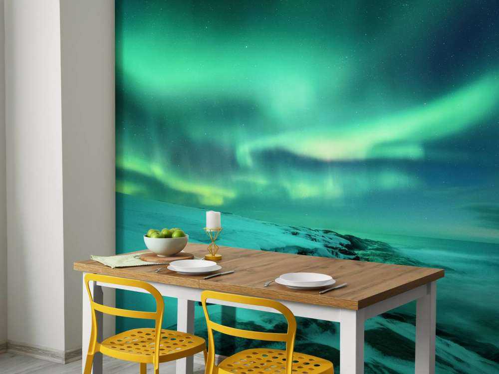 Aurora boreale verde sopra le rocce innevate