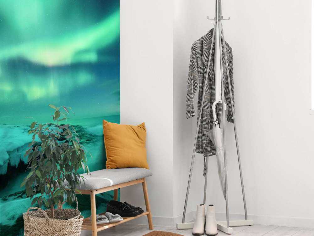 Aurora boreale verde sopra le rocce innevate